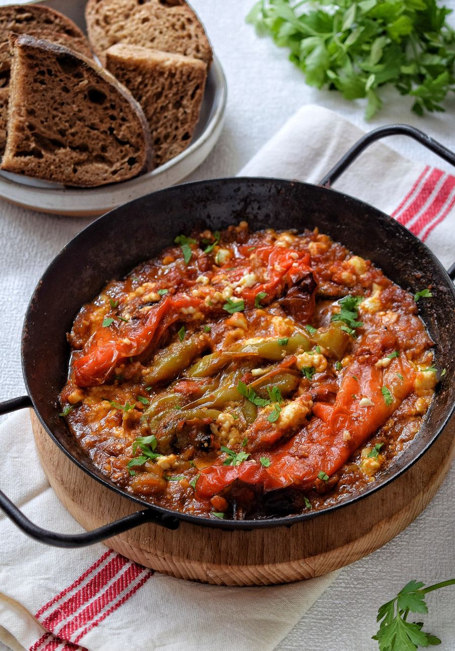 Fërgesë e Tiranës served directly in a hot clay dish with fresh crusty bread.