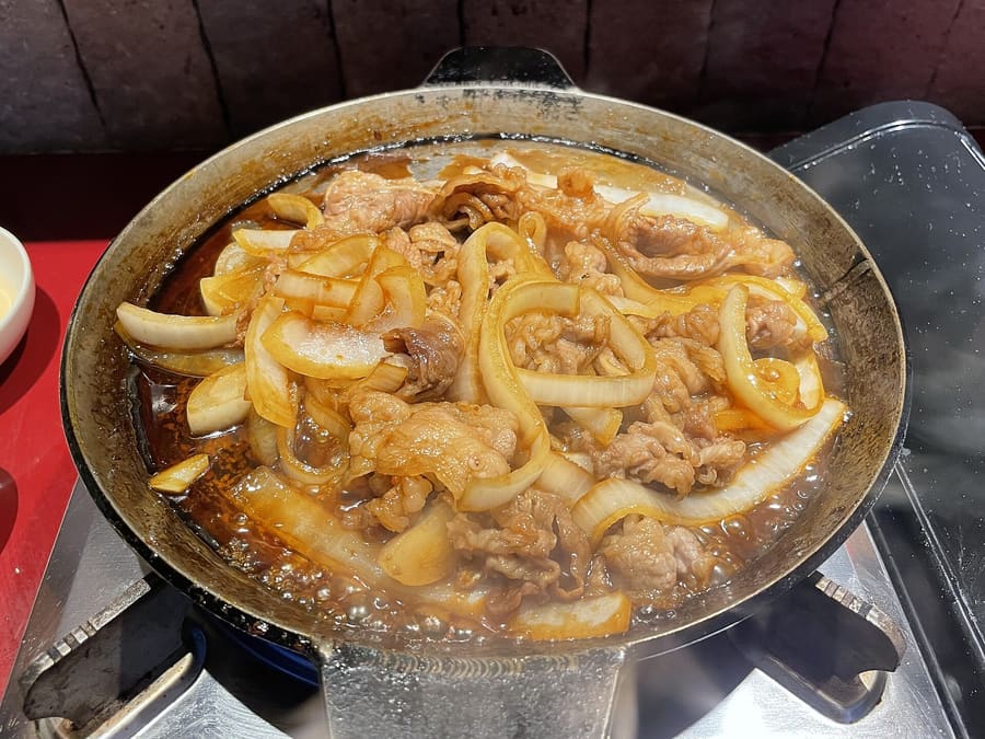 Towada Barayaki sizzles on an iron hotplate with sliced onions and sweet soy glaze.