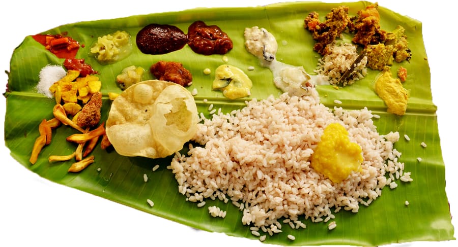 A full Kerala sadya served on a banana leaf, featuring matta rice, avial, and thoran.
