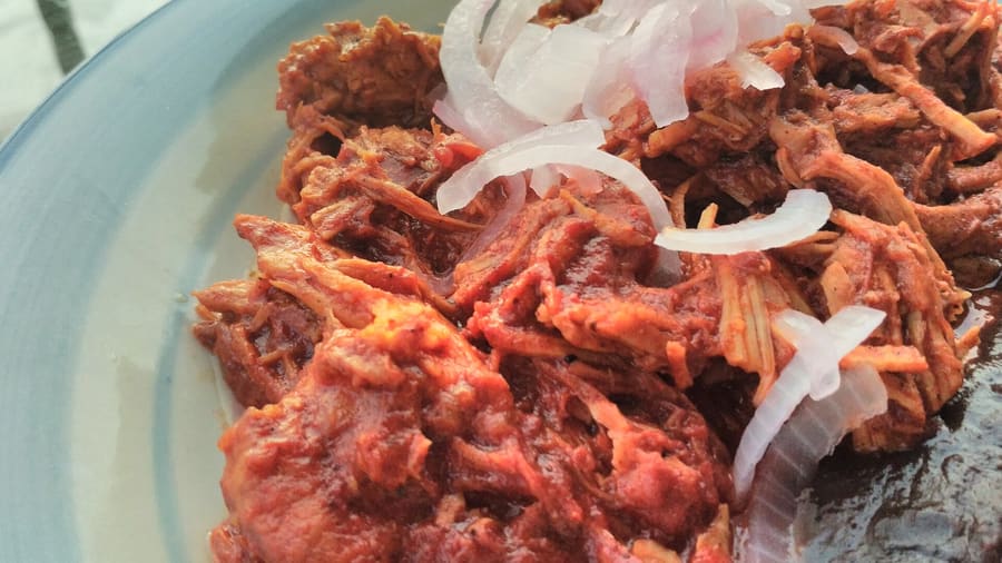 Cochinita pibil tacos served on handmade corn tortillas with pickled red onions.
