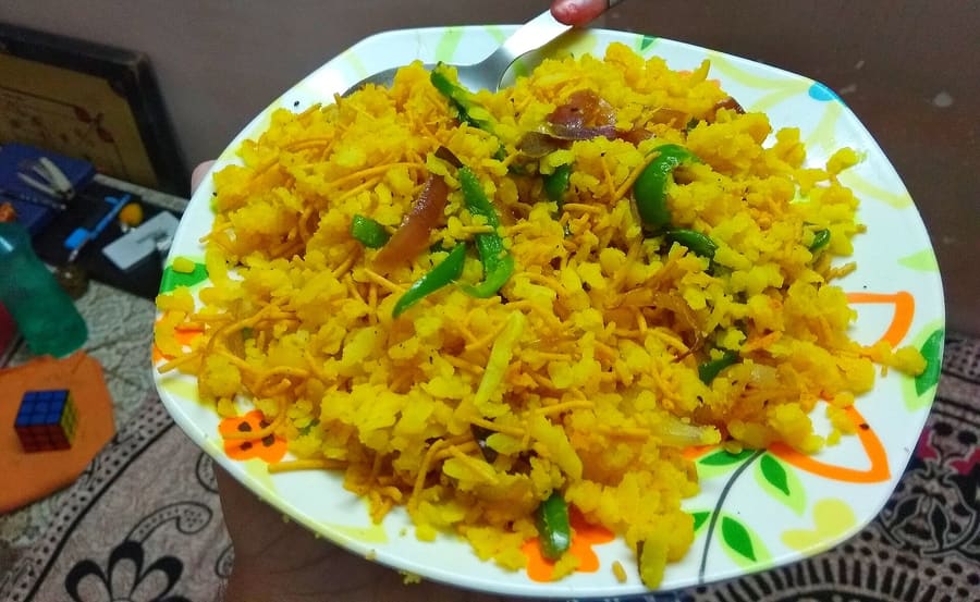 Poha topped with fresh pomegranate seeds and Ratlami sev.