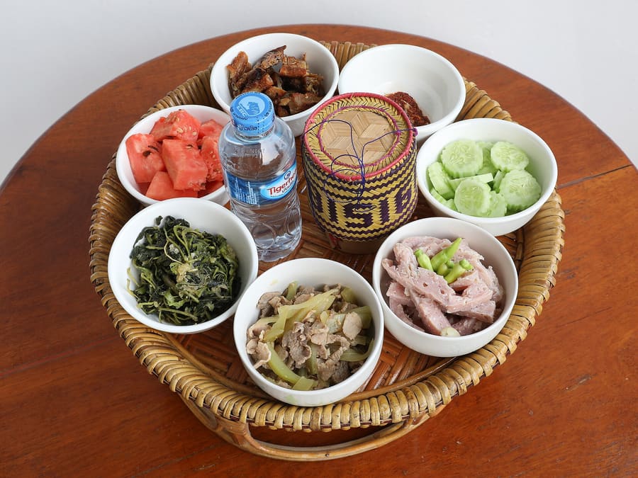 A classic Lao spread featuring laap, sticky rice in bamboo baskets, and fresh herbs.