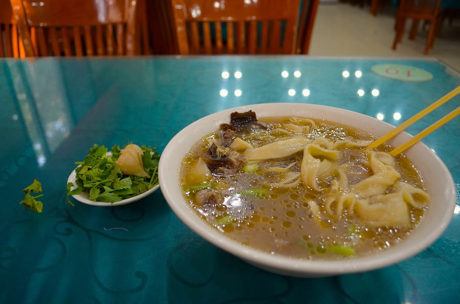 A bowl of traditional Henan Huimian with hand-pulled noodles and lamb broth.